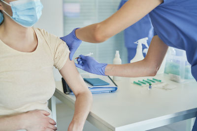 Midsection of female doctor giving vaccination to patient at clinic