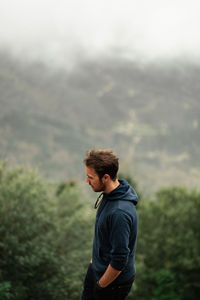 Side view of young man looking away outdoors