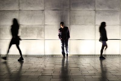 People against illuminated wall at night