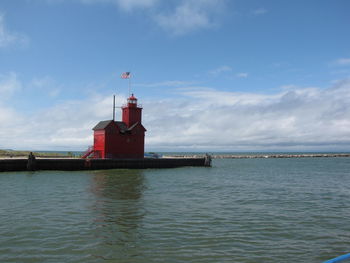 Lighthouse by sea against sky