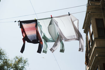 Low angle view of clothes drying on clothesline by building against sky
