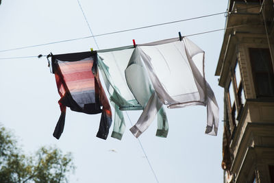 Low angle view of clothes drying on clothesline by building against sky
