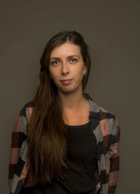 Portrait of young woman standing against gray background