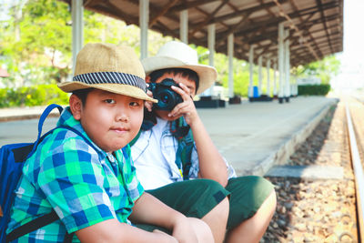 Portrait of cute boy sitting on railroad track