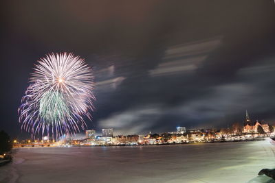 Firework display over illuminated buildings in city at night