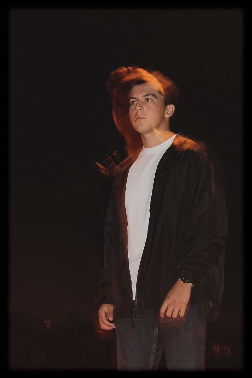 one person, looking, young adult, looking away, standing, studio shot, indoors, three quarter length, black background, young men, front view, auto post production filter, contemplation, lifestyles, transfer print, casual clothing, real people, waist up, hairstyle, stage, profile view