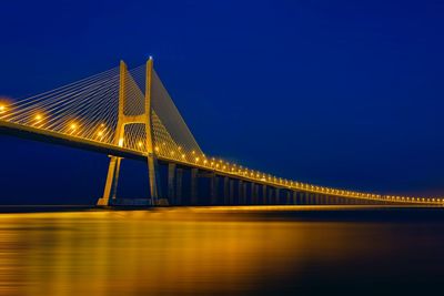 Illuminated bridge over river at night