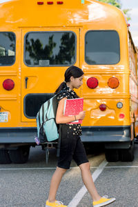 Young girl walking to school near a school bus