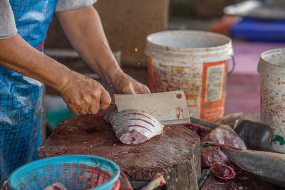 Midsection of man cutting fish at market for sale
