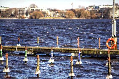 Close-up of wooden posts in sea against sky