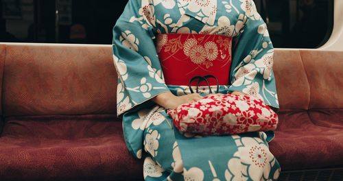 Low section of woman sitting on sofa at home