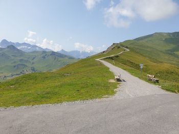 Scenic view of road by mountains against sky