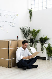 Young man sitting on floor against wall