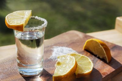 Close-up of tequila shot with lemons slices on cutting board