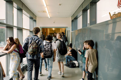 Rear view of students walking in school corridor