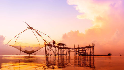 Fishing nets over sea against sky during sunset