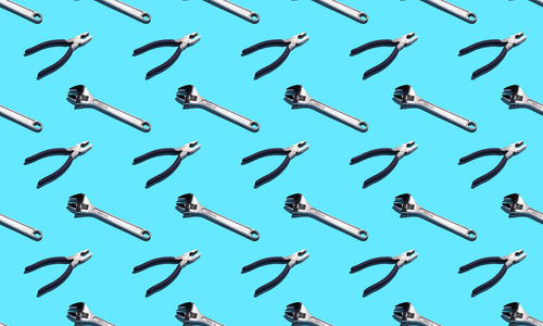 Adjustable wrenches and pliers on a blue background, pattern, hard shadows. construction tools