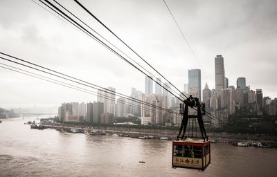 Overhead cable car over river with city in background