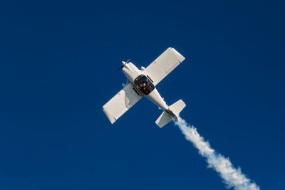 Low angle view of airplane flying against clear blue sky