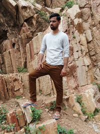 Young man standing on rock against wall