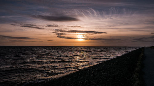 Scenic view of sea against dramatic sky during sunset