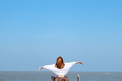 Rear view of woman in sea against clear sky