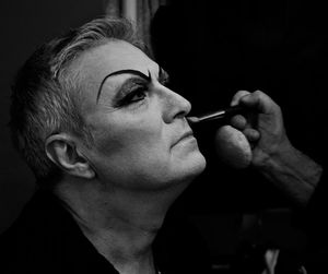 Cropped hands applying face paint to man