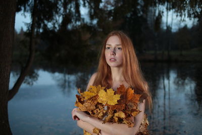 Portrait of young woman in park during autumn