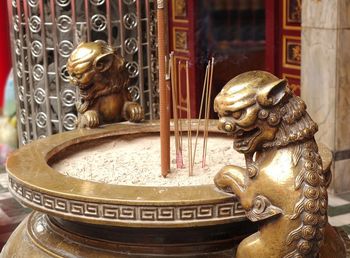 Incenses in cauldron amidst statues outside temple