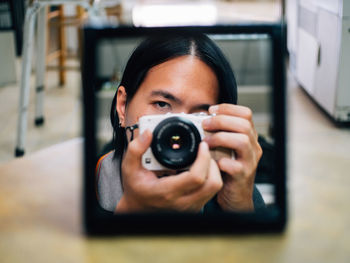 Man photographing while reflecting in mirror