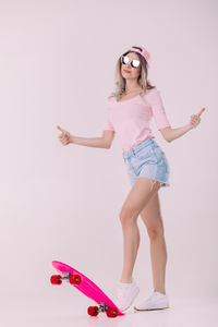 Portrait of young woman standing against white background