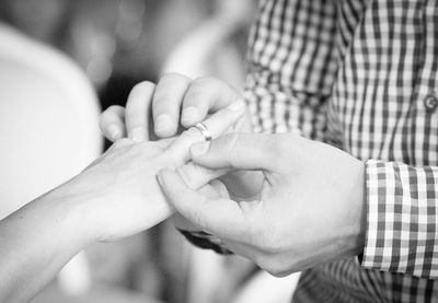 Midsection of man putting ring in woman finger