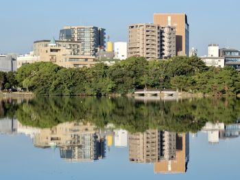 Reflection of buildings and trees in lake against sky