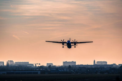 Airplane flying in sky at sunset