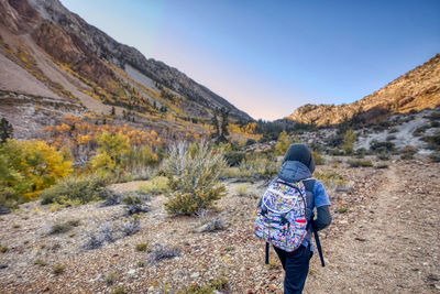 Rear view of woman standing on mountain against sky