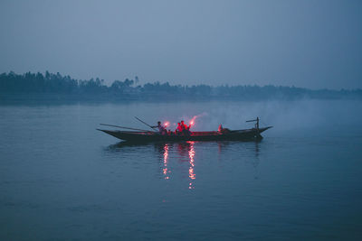 People in boat sailing on sea against sky