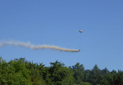 Low angle view of airplane flying against clear blue sky