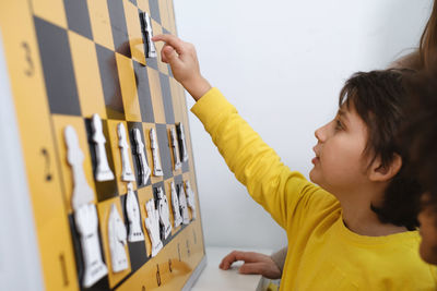 Child thinking hard on chess combinations on the wall on tournament for kids intellectual game