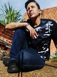 Young man looking away while sitting outdoors