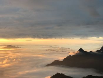 Scenic view of dramatic sky over silhouette mountains during sunset