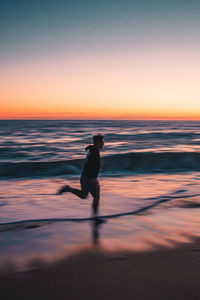 Silhouette man on beach against sky during sunset