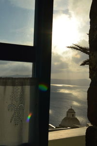 Close-up of cross against sky seen through window