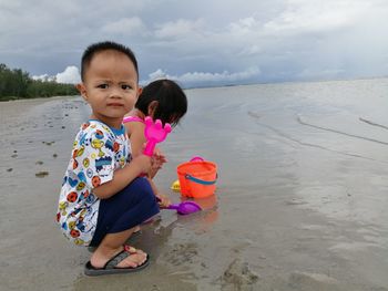 Cute baby girl on beach against sky