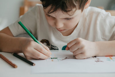The boy draws with pencils at the kitchen, closeup. high quality photo