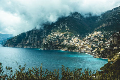 Scenic view of townscape by sea against mountain