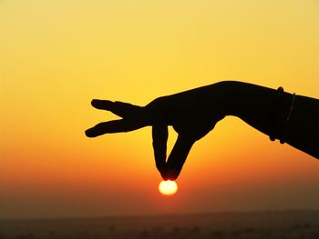 Silhouette hand of woman gesturing against sky during sunset