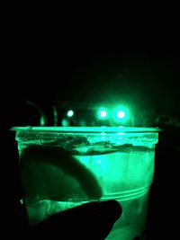 Close-up of hand against illuminated lights over sea