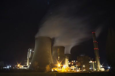 Low angle view of illuminated factory against sky at night