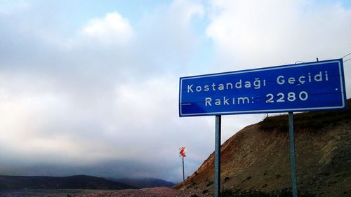 Information sign on mountain road against sky