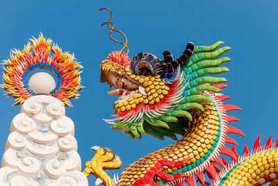 Sculpture of colorful dragon against a blue sky